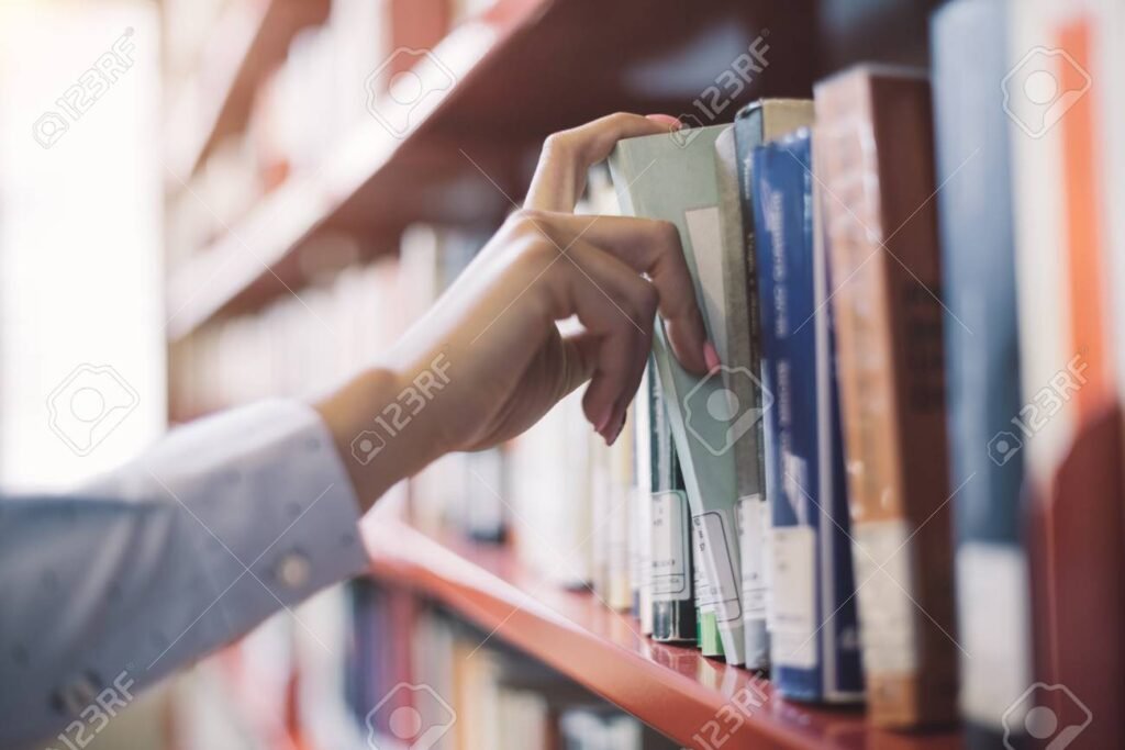 manos buscando libros en una biblioteca